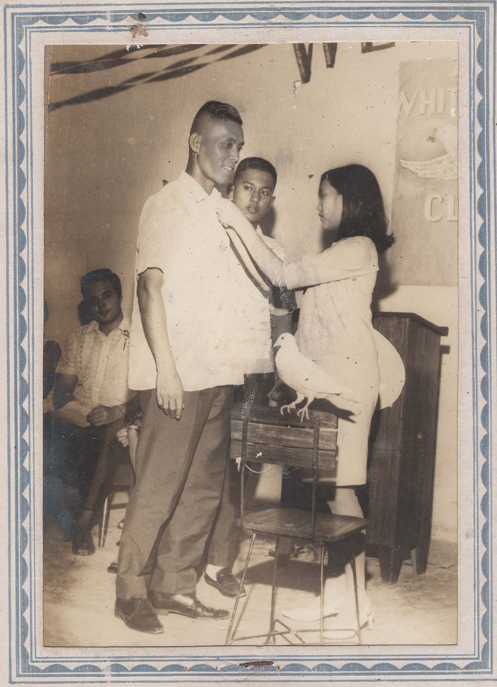 A man having a sash placed on him, with a white dove nearby